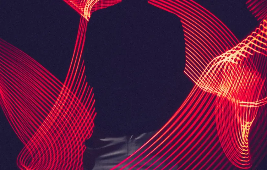 A silhouette of a person surrounded by artistic red light trails, creating a dynamic visual effect.